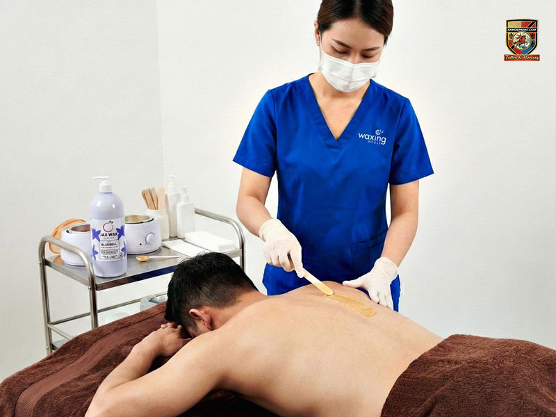 Kỹ thuật viên tại địa chỉ triệt lông mọc ngược uy tín đang waxing lưng cho nam giới với sản phẩm chuyên dụng.