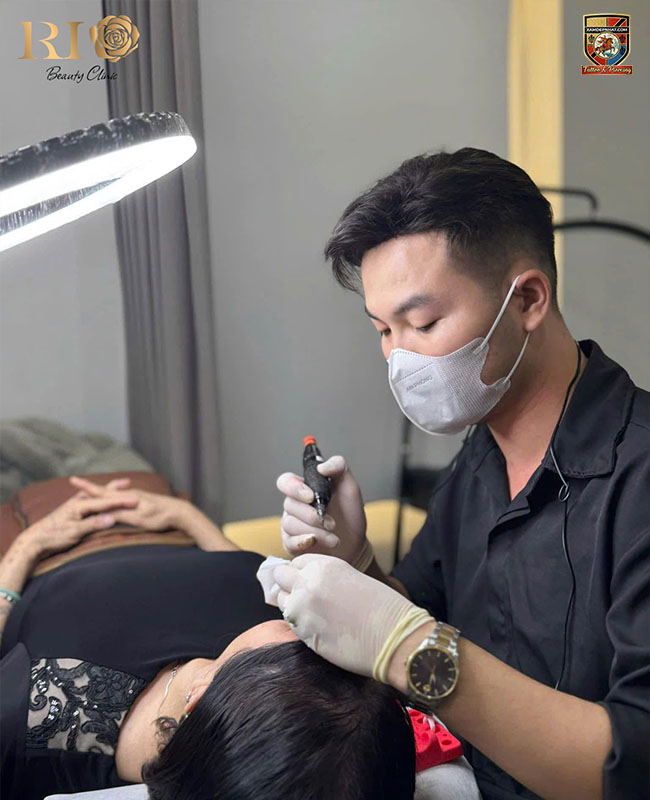 Kỹ thuật viên thực hiện phun thêu cho khách hàng tại Rio Beauty Clinic, địa chỉ điêu khắc chân mày uy tín.