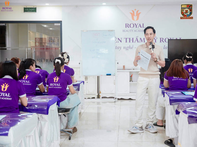Giảng viên tại Royal Beauty Academy đang giảng bài trước lớp học viên mặc đồng phục tím
