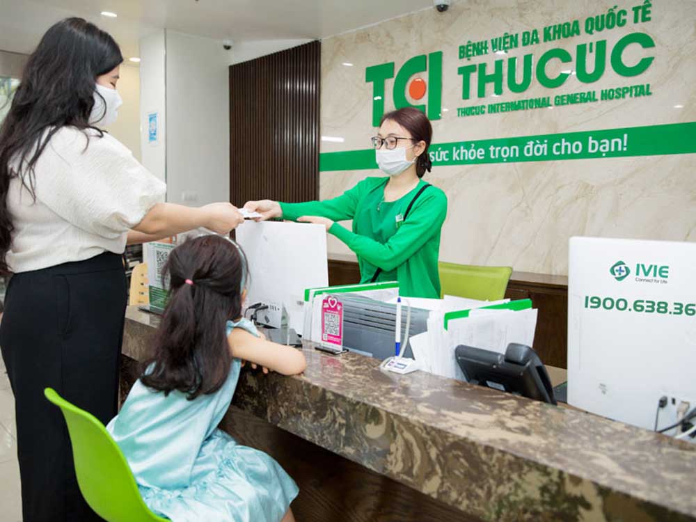 Front desk receptionist assisting a mother and child at Thu Cuc International General Hospital, one of the best melasma clinics in Hanoi