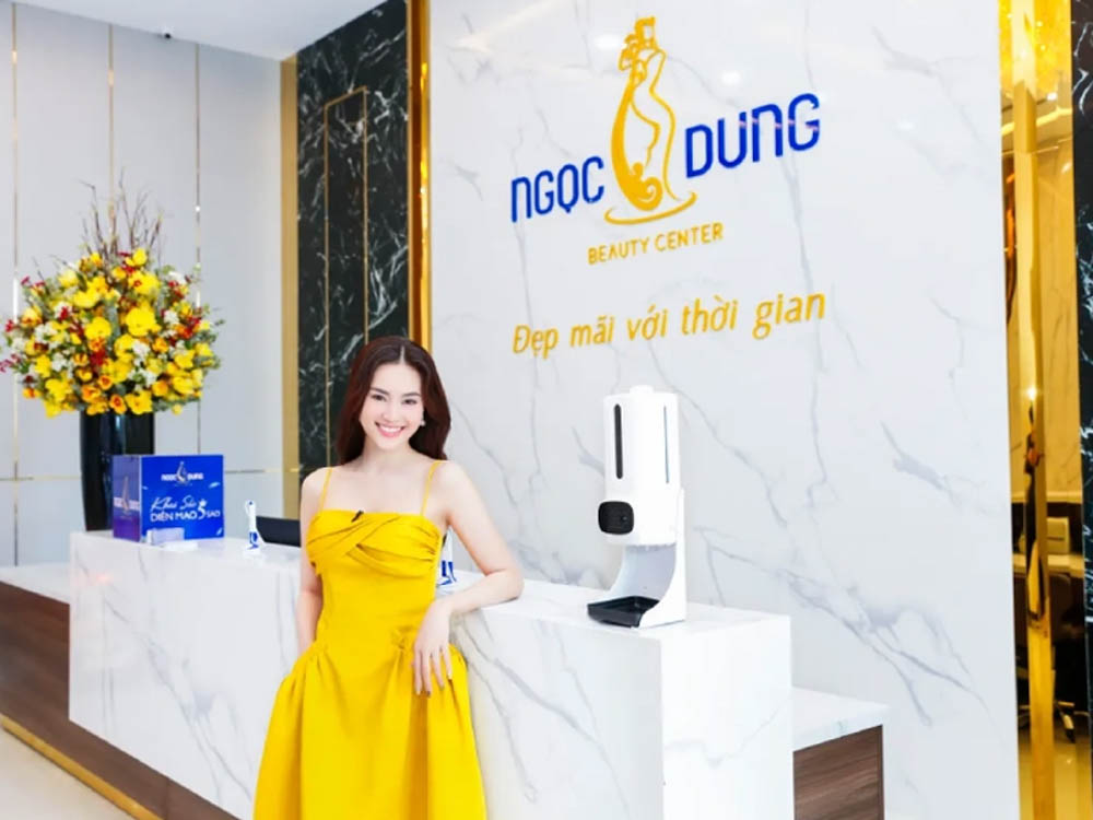 Brand ambassador smiling beside the marble front desk at Ngoc Dung Beauty Center