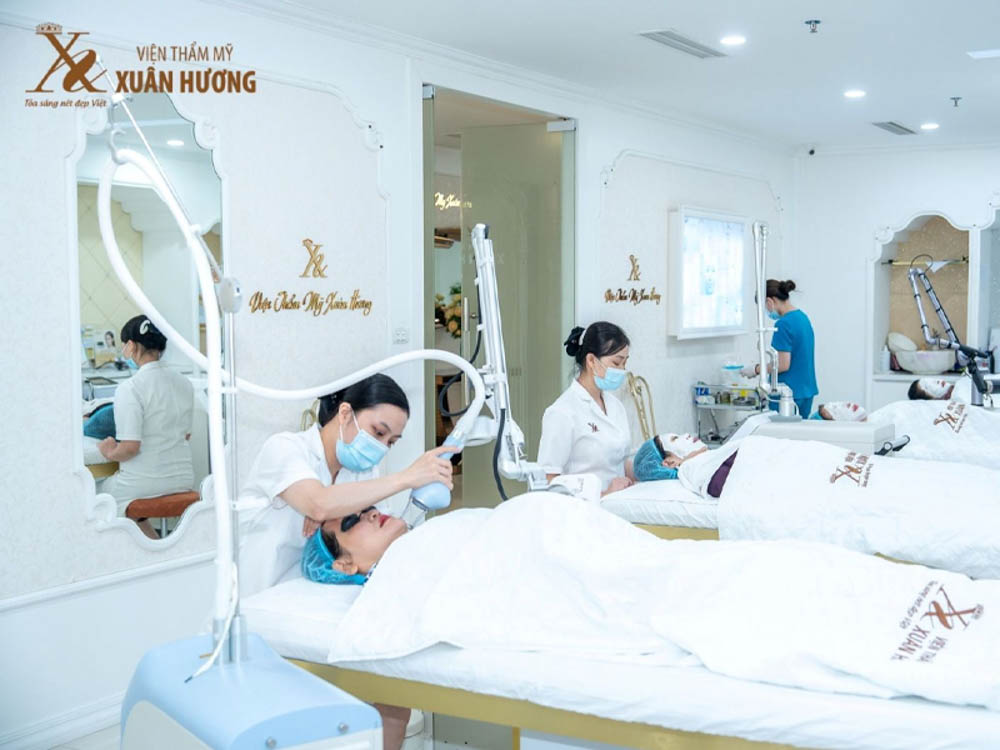 Practitioners delivering laser toning procedures to clients in the treatment room of Xuan Huong Beauty Clinic