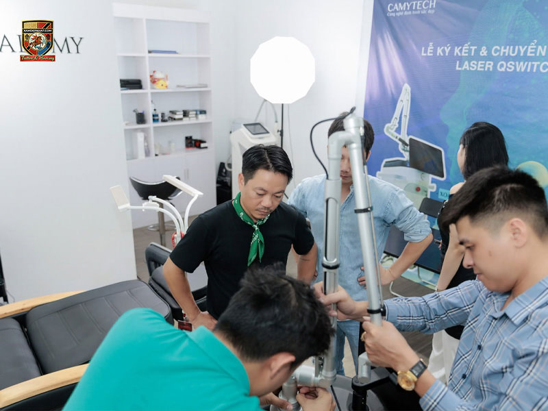 Instructors and technicians adjusting an articulated laser arm at Camytech Academy during advanced aesthetic technology training. best scalp micropigmentation training in Hanoi