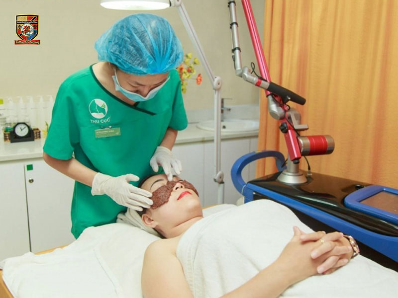 Kỹ thuật viên Thu Cúc mặc áo xanh lá đeo găng tay y tế cẩn thận đắp mặt nạ dưỡng phục hồi da cho khách hàng