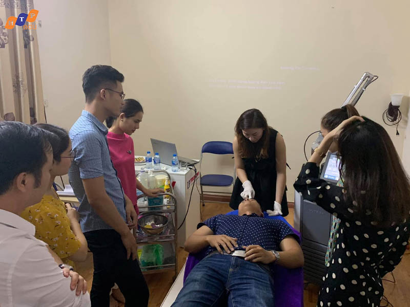 Trainees gathered around an instructor demonstrating laser equipment operations on a model