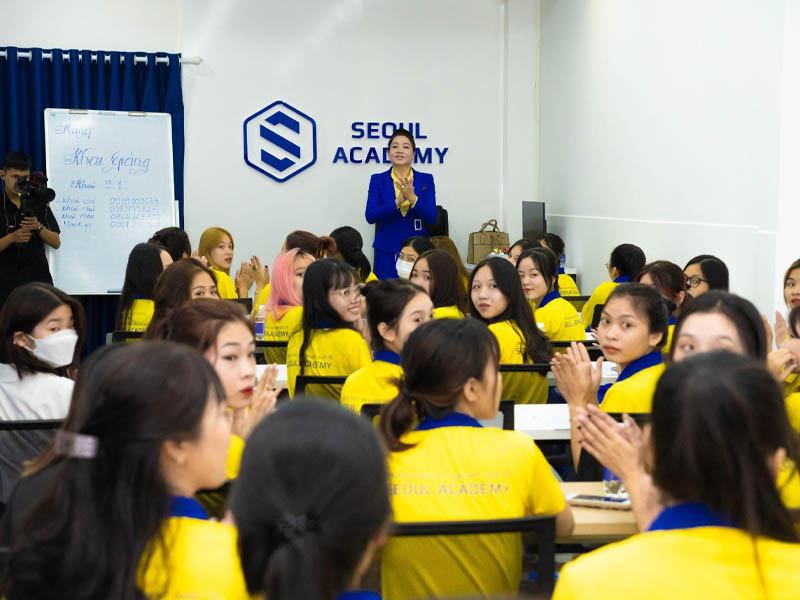 Seoul Academy students in yellow uniforms applauding during a lively classroom session